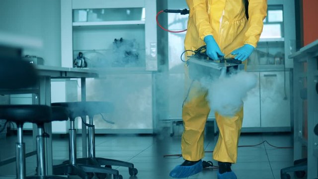 Disinfector cleans classroom with a sprayer.