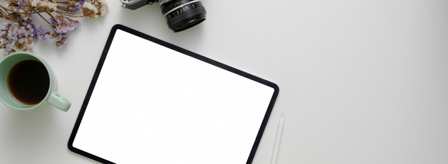 Top view of modern workspace with mock-up tablet, coffee cup, camera, coffee cup and copy space