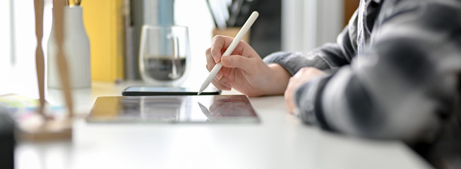 Side view of female graphic designer working on digital tablet on white worktable
