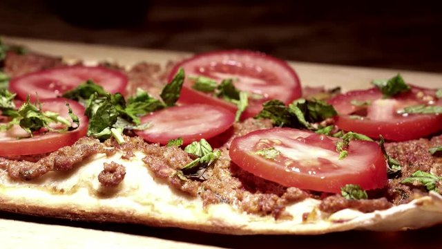 Panning on Turkish pizza lahmacun with black background.
