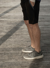 Person male man in sneakers and shorts and hoodie looking out over the ocean sea on a jetty at Semaphore in Adelaide South Australia at late afternoon sunset