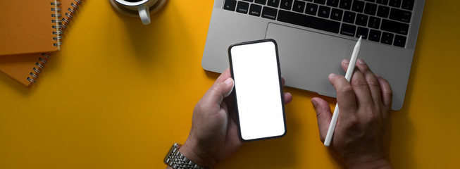 Overhead shot of businessman working with blank screen smartphone and laptop