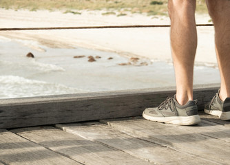 Person male man in sneakers and shorts and hoodie looking out over the ocean sea on a jetty at Semaphore in Adelaide South Australia at late afternoon sunset