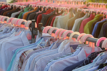 Fototapeta premium Huge selection of different used clothes for men, women and children on the rack in a second hand shop or thrift store. Concept of waste problem in fashion industry.