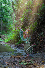 Beautiful Thai young woman portrait in Kinnaree traditional dress costume of Thailand standing in forest, Kinnaree is a fairy tale animal with a human body, but the tail is a bird.