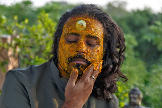 Face Portrait Of Attractive Bearded Indian Man Applying Facial Clay Mask With Turmeric And Cucumbers