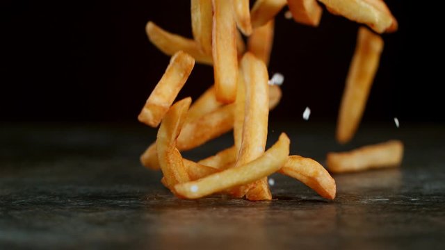 Super Slow Motion Shot of Falling Fresh French Fries on Stone Table at 1000fps.