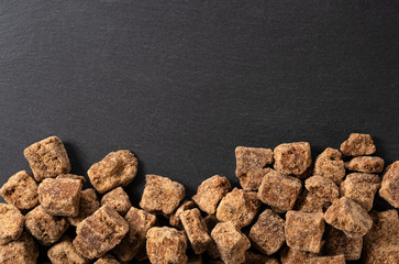 Take a bird's eye view of a block of brown sugar placed on a black background with copy space