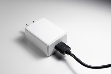 White charger adapter and black USB cable on a white background The concept of charging technology...