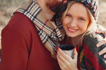 Couple by the tree. People in a spring forest. Pair with thermos.