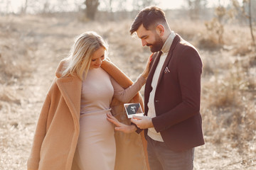 Woman in a brown coat. People in a spring forest. Family holding ultrasound.
