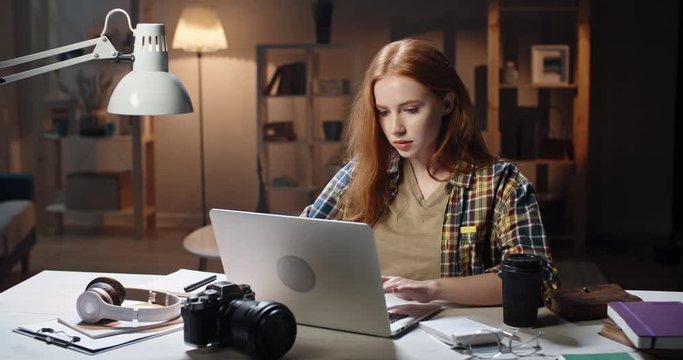 Cute caucasian girl concentrating on work at desk, using laptop to prepare for school or university exam, young freelancing manager working on a project 4k footage