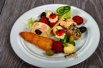food platter with meat and cheese rolls and vegetables with sauces