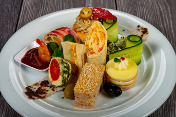 food platter with meat and cheese rolls and vegetables with sauces