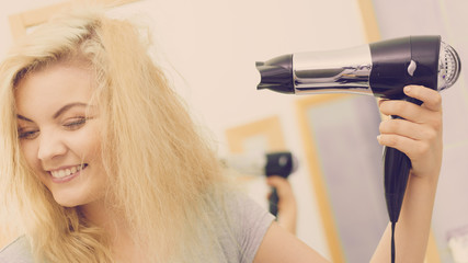Blonde woman using hair dryer