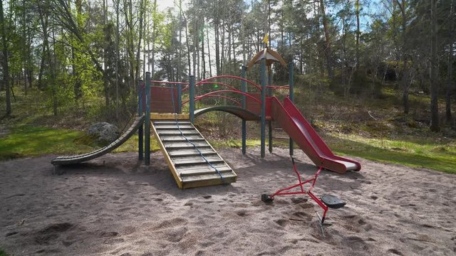 A empty playground in a big sandbox with ropes, bridge and slider.  Red toy excavator in the foreground. No children is playing dou to the corona crises. Camera pan out. 4K