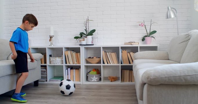 A six years old boy playing soccer football at home during quarantine COVID-19. Life stile in an apartment. 4k