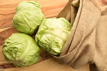 Fresh green cabbage with a jute bag, on a wooden table.