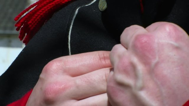 French Napoleon soldier closes the buttons of his costume. Close shot on hands.