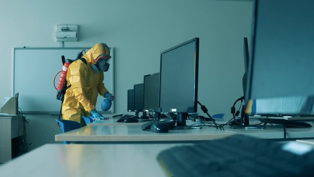 Worker cleans desks with monitors to kill virus.
