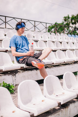 young guy is resting on the podium of the stadium after running