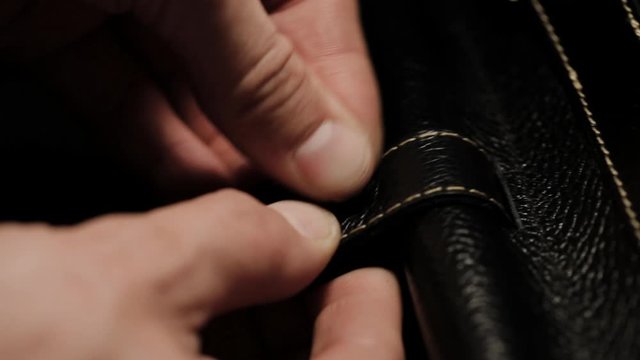 installing the rivet in the leather. The master makes a leather bag close-up. mounting the handle for the bag