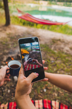 woman taking picture of metal camping mugs on phone