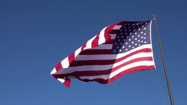 American flag against blue sky Flowing in the Wind at Slow Motion