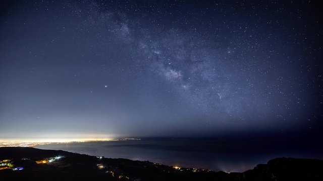 Time Lapse of the starry night sky and the Milky Way rising over the glowing lights of Los Angles