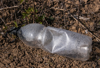 crumpled empty plastic bottle lies on the ground