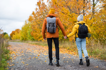 back view of couple hikers with backpacks hiking in forest