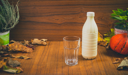 Fresh homemade natural youghurt drink in plastic container with a glass standing next to it. Beautiful autumn setting table for yoghurt drink. Fresh and good drink for digestion concept.
