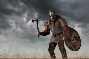 Warrior Viking in full arms with axe helmet and shield on dark sky background. Medieval...