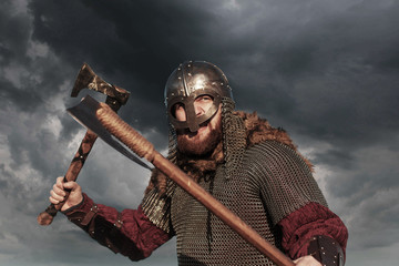 Warrior Viking in full arms with axe helmet and shield on dark sky background. Medieval...