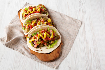 Homemade Cheeseburger Tacos on a rustic wooden board on a white wooden background, low angle view. Copy space.