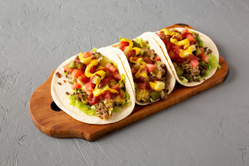 Homemade Cheeseburger Tacos on a rustic wooden board on a gray background, low angle view. Close-up.