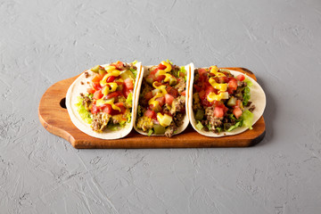 Homemade Cheeseburger Tacos on a rustic wooden board on a gray background, low angle view.