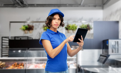 Fototapeta na wymiar mail service, technology and shipment concept - delivery girl in blue uniform with tablet pc computer over grocery store on background