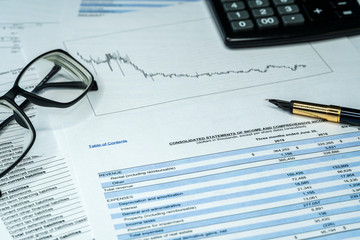 Income statement financial report with pen and glasses. Investment analysis