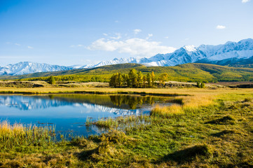 lake and mountains, Altai, autumn day. Reflections in the lake, yellow withered grass.