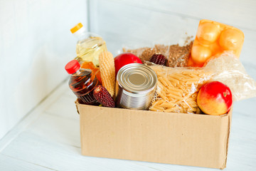 stock food at the isolation, the delivery of food in a crisis, coronavirus pandemic, food box on a white wooden background
