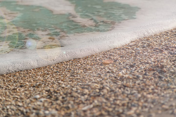 Ocean wave on a sandy beach in the sunset light for background use
