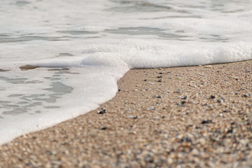 Ocean wave on a sandy beach in the sunset light for background use