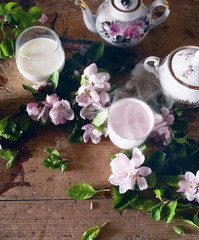 Obraz na płótnie Canvas Pink tea and apple tree flowers on a wooden table