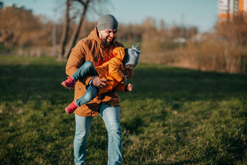 Father and daughter playing in park on green grass. Father's day. Little girl plays with dad outside. Father and daughter playing tag in park.