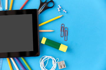 education, technology and object concept - tablet pc computer and stationery or school supplies on blue background