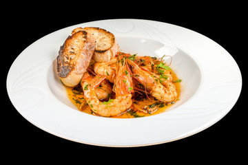 Gourmet shrimp with butter and garlic on a plate, isolated on black background