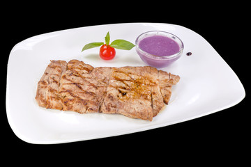 Tasty pork with blueberries on a plate, isolated on black background.