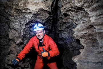 Man walking and exploring dark cave with light headlamp underground. Mysterious deep dark, explorer...