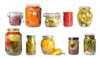 Set of jars with pickled vegetables and feta cheese on white background